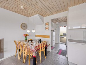 A dining area with a wooden table, chairs, and a vase of flowers. - 4 Star Holiday Home in Lokken (Lokken)