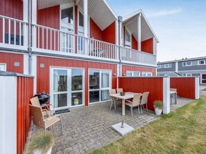 A red building with a balcony, outdoor seating, and a barbecue grill. - 4 Star Holiday Home in Lokken (Lokken)