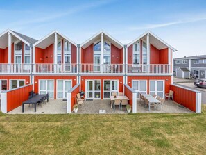A two-story building with a red exterior, balconies, and outdoor seating areas. - 4 Star Holiday Home in Lokken (Lokken)