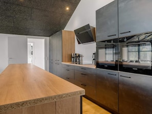 A modern kitchen with a wooden countertop, dark cabinetry, and a built-in oven. - 4 Star Holiday Home in Lokken (Lokken)