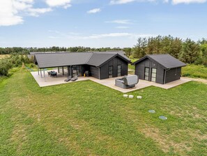 A modern two-story house with a patio, outdoor seating, and a large outdoor heater. - 4 Star Holiday Home in Lokken (Lokken)