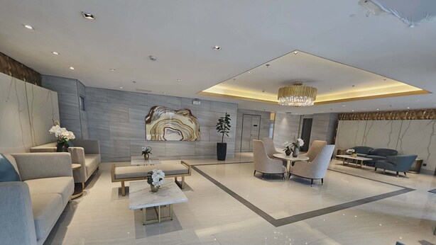 A modern hotel lobby with seating areas, a chandelier, and a marble wall. - Casa Rogelio at Fame Residences Tower 4 (Mandaluyong)