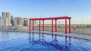Ein Dachpool mit roter Pergola, im Hintergrund die Stadtlandschaft.