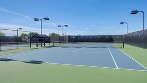 An outdoor tennis court with a net, surrounded by a fence, and equipped with street lamps. - On Johnson Ranch Golf Course: San Tan Valley Home (San Tan Valley)
