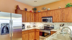 A kitchen with wooden cabinets, a stainless steel refrigerator, a microwave, and a stove. - On Johnson Ranch Golf Course: San Tan Valley Home (San Tan Valley)