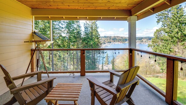 Une terrasse en bois avec deux fauteuils Adirondack et une petite table, donnant sur un lac et une zone boisée.