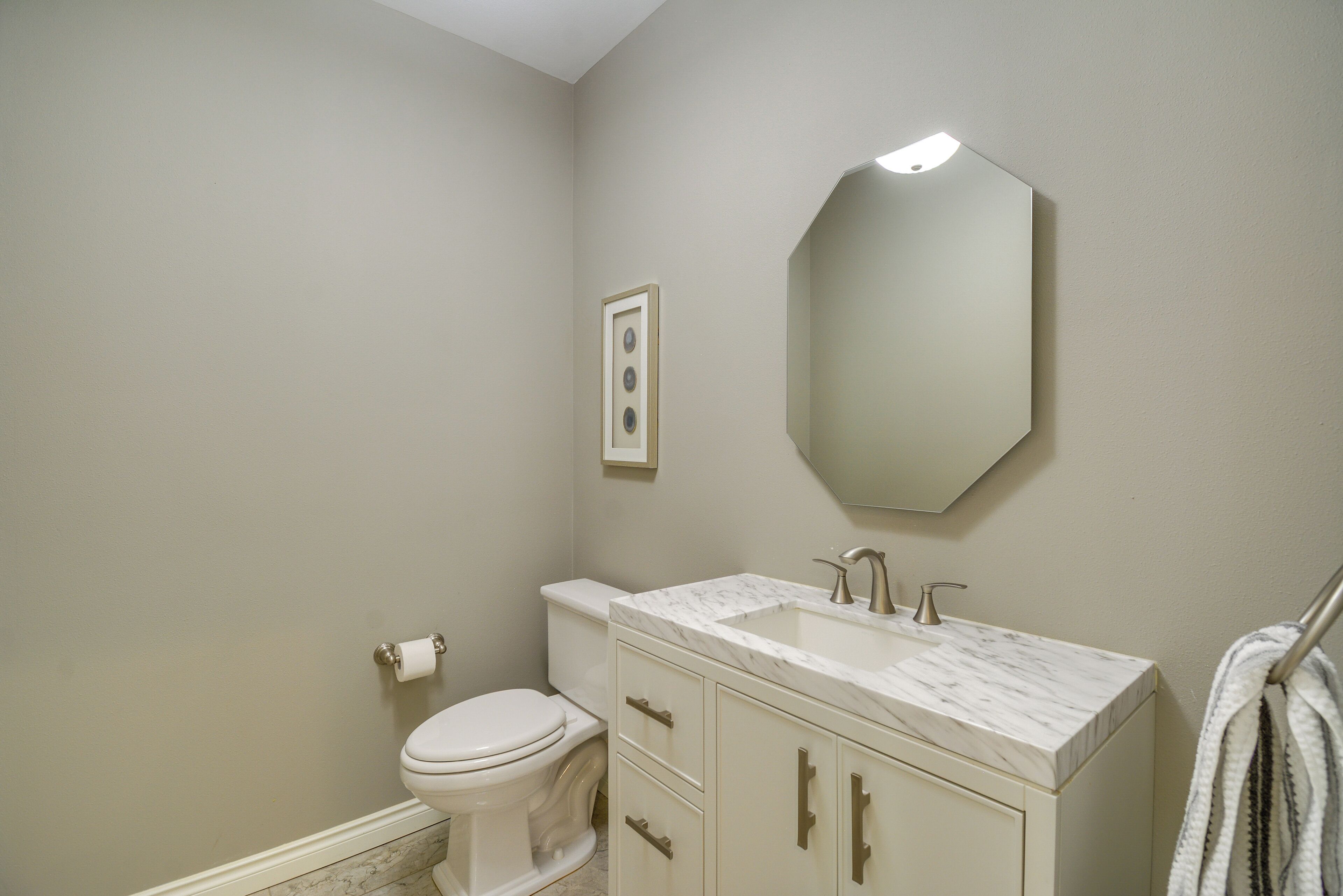 A bathroom with a toilet, sink, mirror, and towel rack.