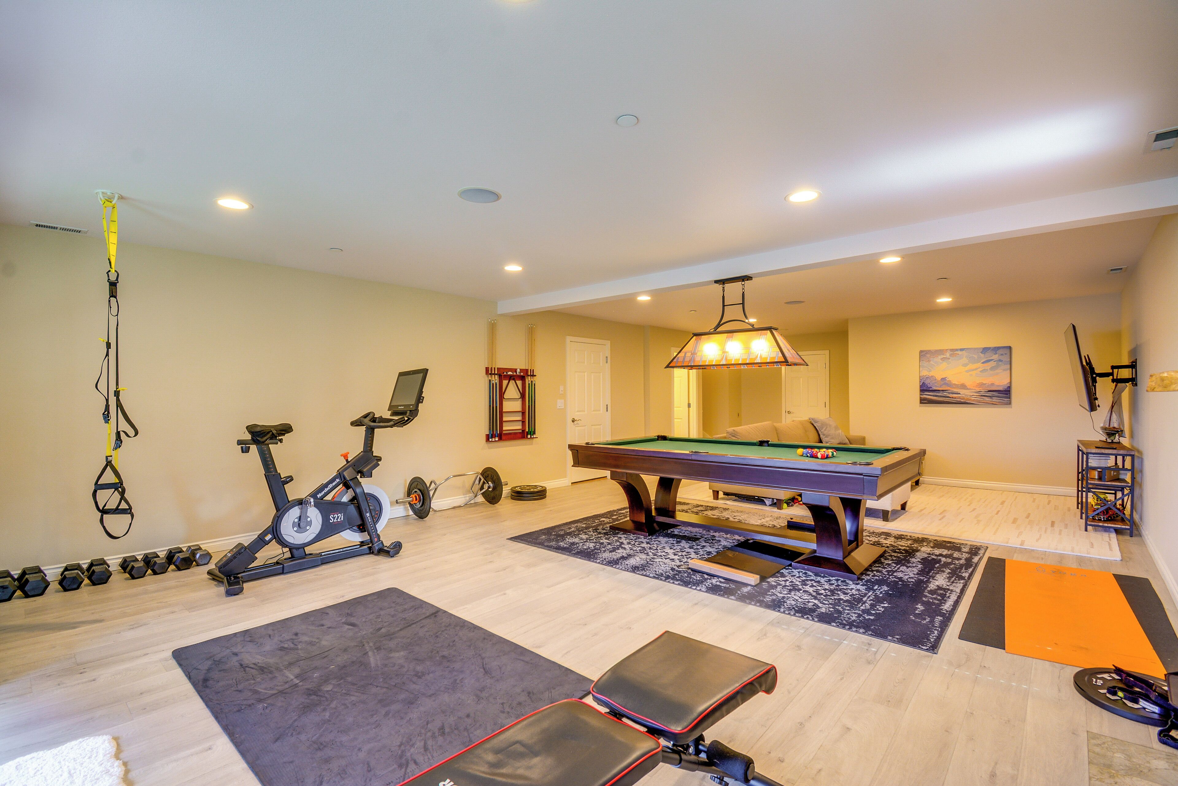 A home gym with exercise equipment, a pool table, and a billiards table.
