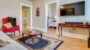 A living room with a red sofa, a coffee table, a TV mounted on the wall, and a wooden cabinet. - Historic Lebanon Gem: Central Walkable Location! (Lebanon)
