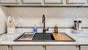 A kitchen with a black faucet, a marble countertop, a knife block, a cutting board, and a spice rack. - Historic Lebanon Gem: Central Walkable Location! (Lebanon)