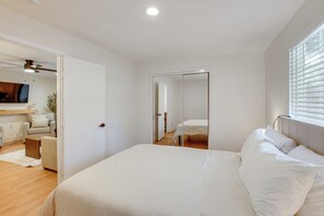 Ein Schlafzimmer mit einem Bett, einem Spiegel, einem Deckenventilator und einem Fenster mit Jalousien.