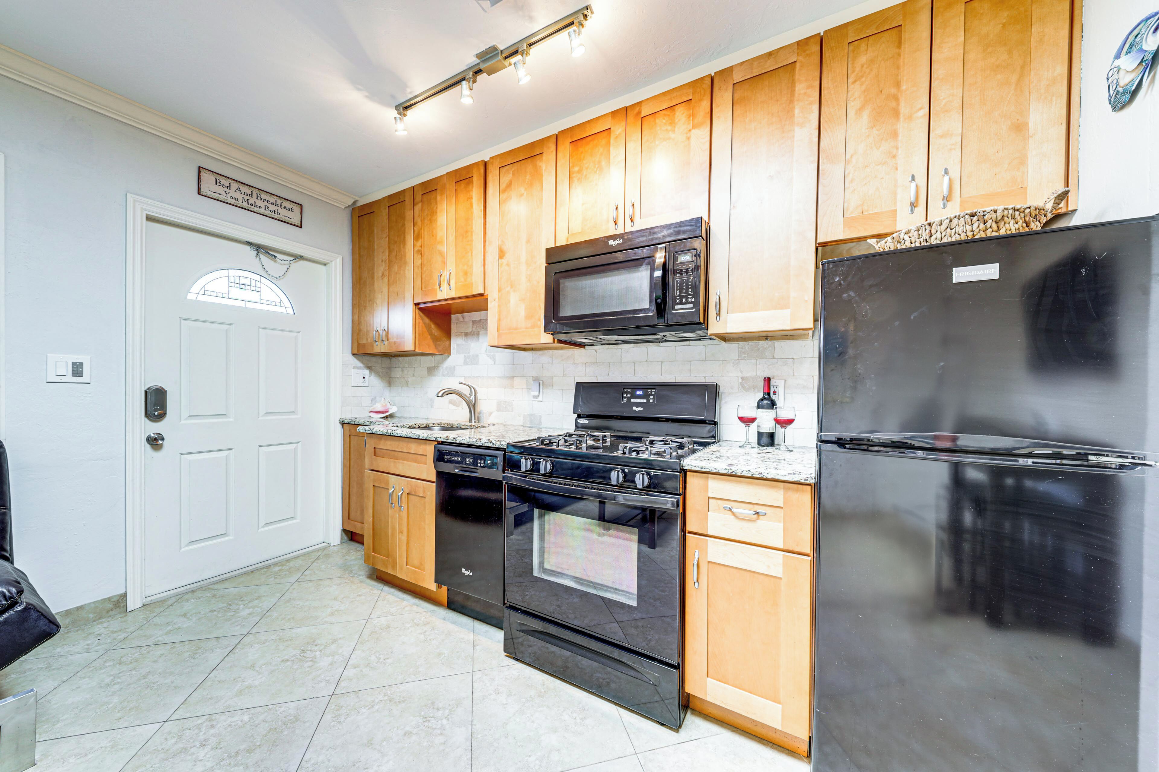 A kitchen with wooden cabinets, a black refrigerator, a microwave, a stove, and a dishwasher.