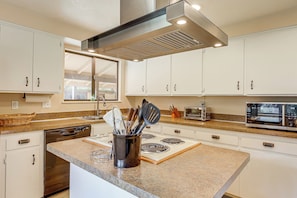 A modern kitchen with white cabinets, a stainless steel range hood, a built-in oven, and a microwave.