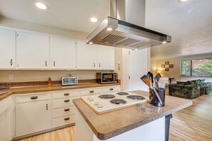 A kitchen with white cabinets, a microwave, a stove, and a countertop with kitchen utensils. - Creative Escape! Eagle's Nest Hideaway (Cottage Grove)