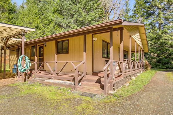 A wooden cabin with a porch, a hose, and a gravel path. - Creative Escape! Eagle's Nest Hideaway (Cottage Grove)