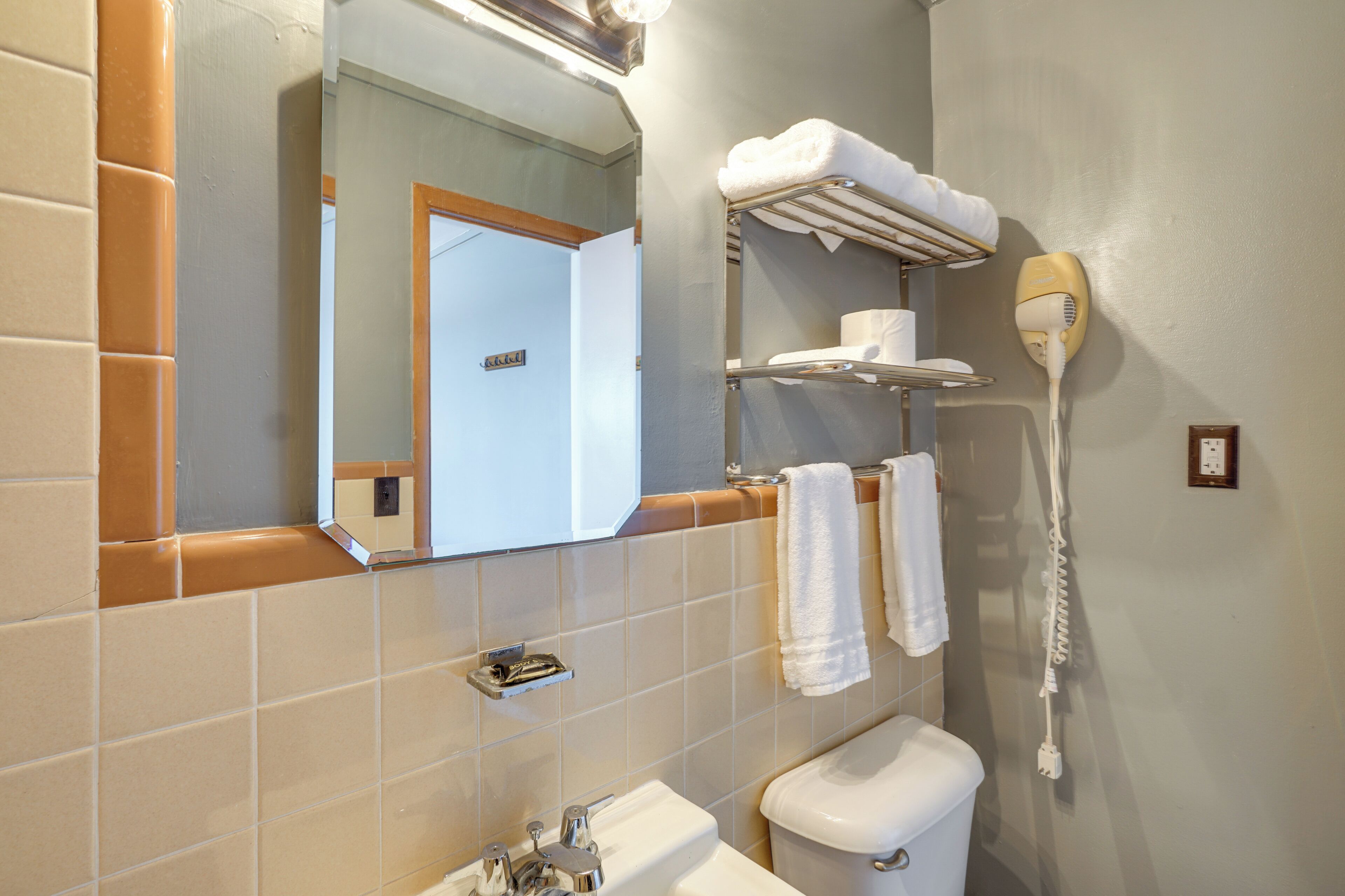A bathroom with a sink, toilet, towel rack, and a hairdryer.