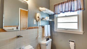 A bathroom with a toilet, a sink, a mirror, a towel rack, and a window with curtains.