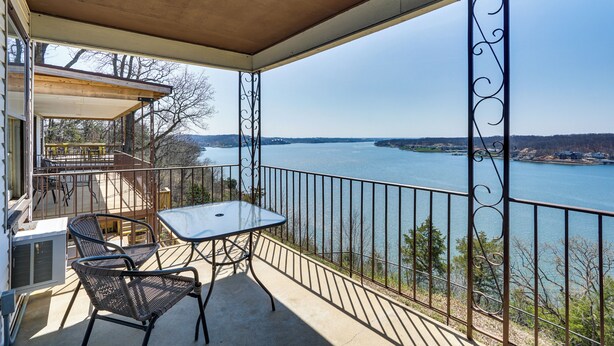 A balcony with a table and chairs, overlooking a body of water and distant land. - Main-channel Views for Lake Ozark Shootout Weekend (Lake Ozark)