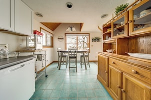 Una cocina con una mesa de comedor, sillas, armarios y lavavajillas.