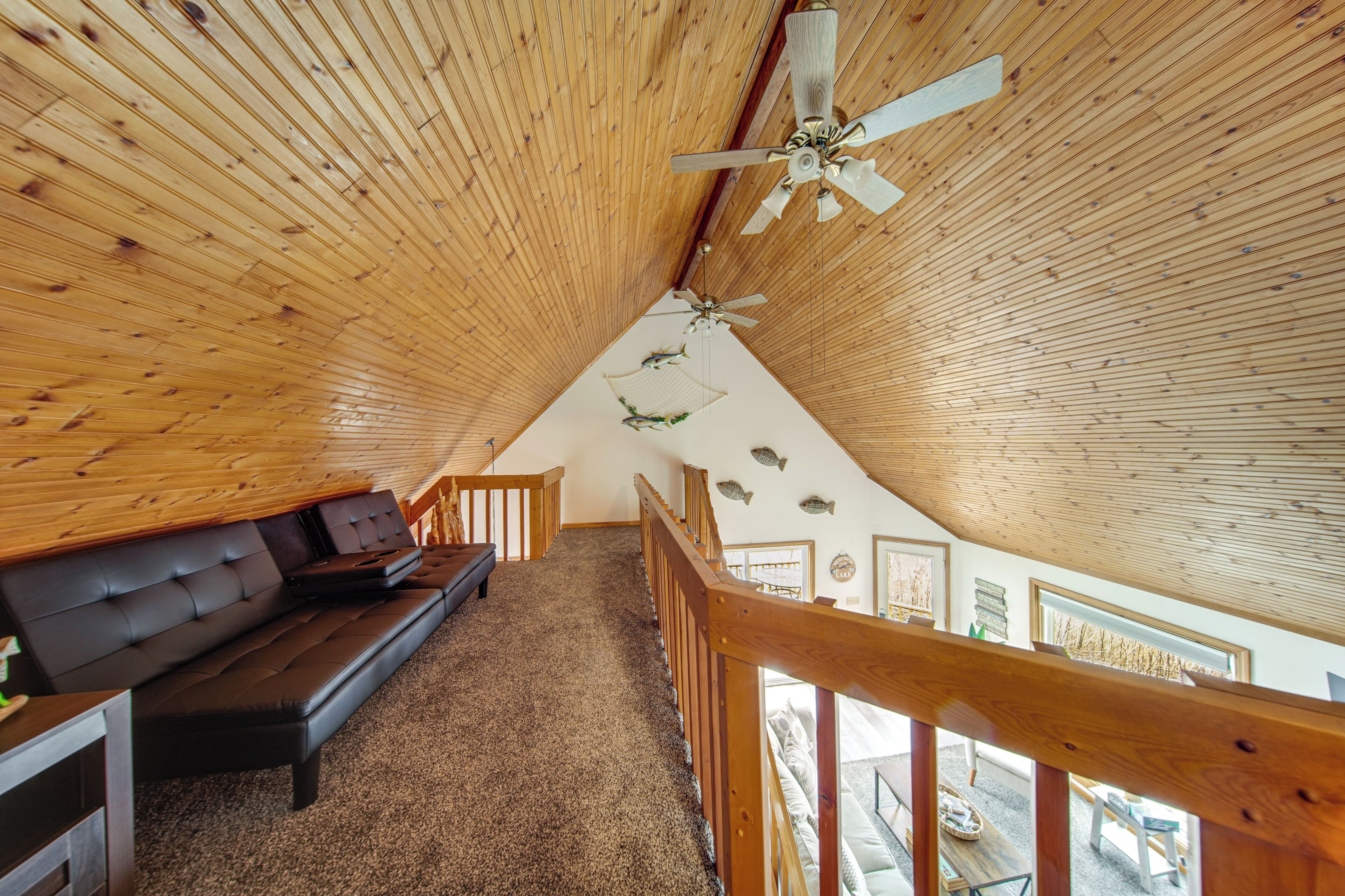 Interior de madera con un sofá, ventiladores de techo y vistas al exterior.