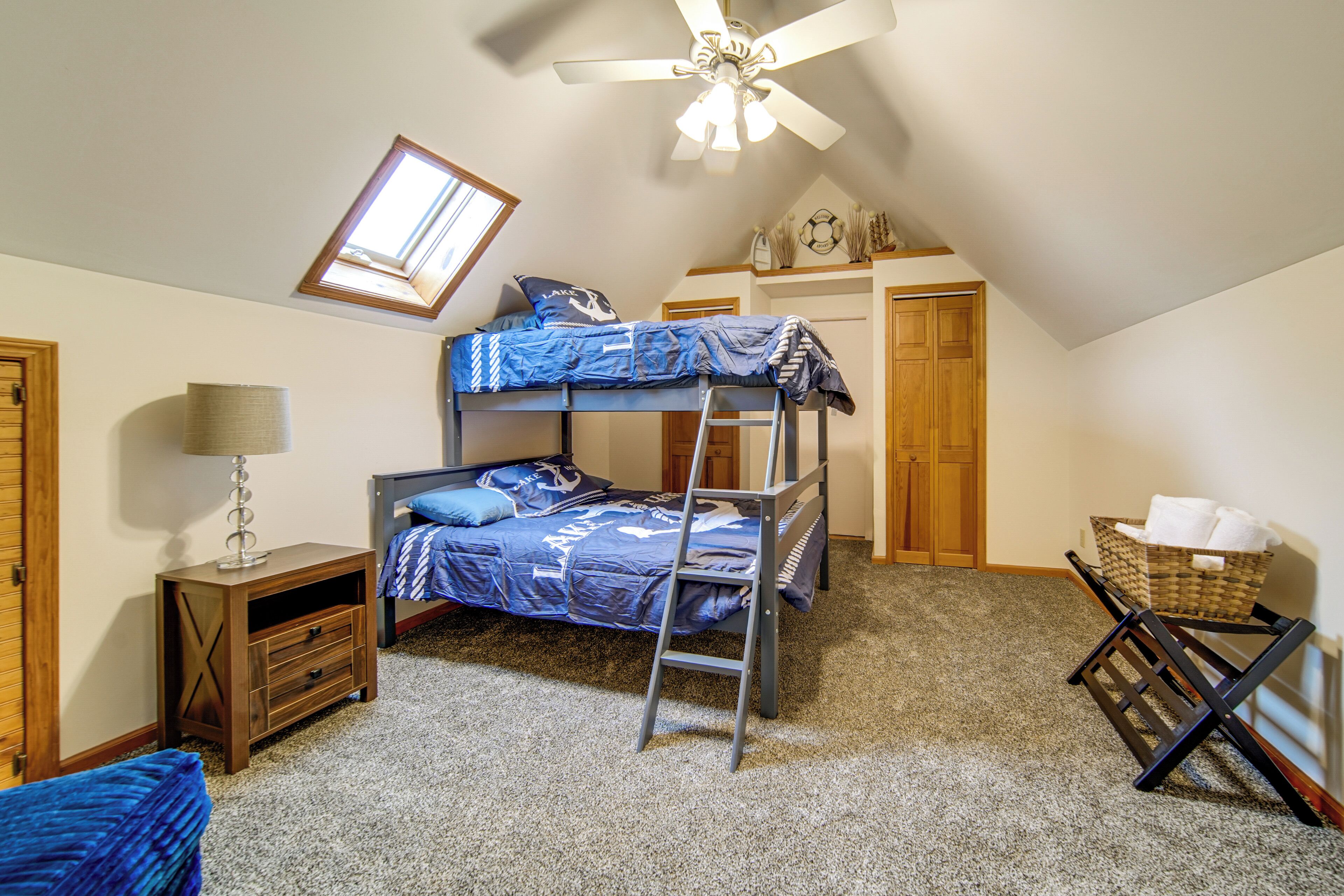 Ein Mehrbettzimmer mit Schiebedach, Deckenventilator, Schreibtisch mit Lampe und kleinem Stauraum.