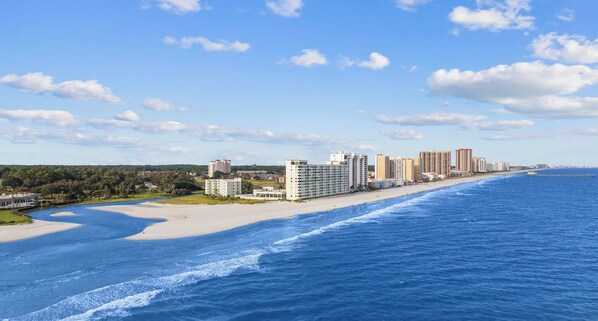 Eine Küstenstadt mit einem Hotel am Strand, einem Sandstrand und einem klaren, blauen Meer.