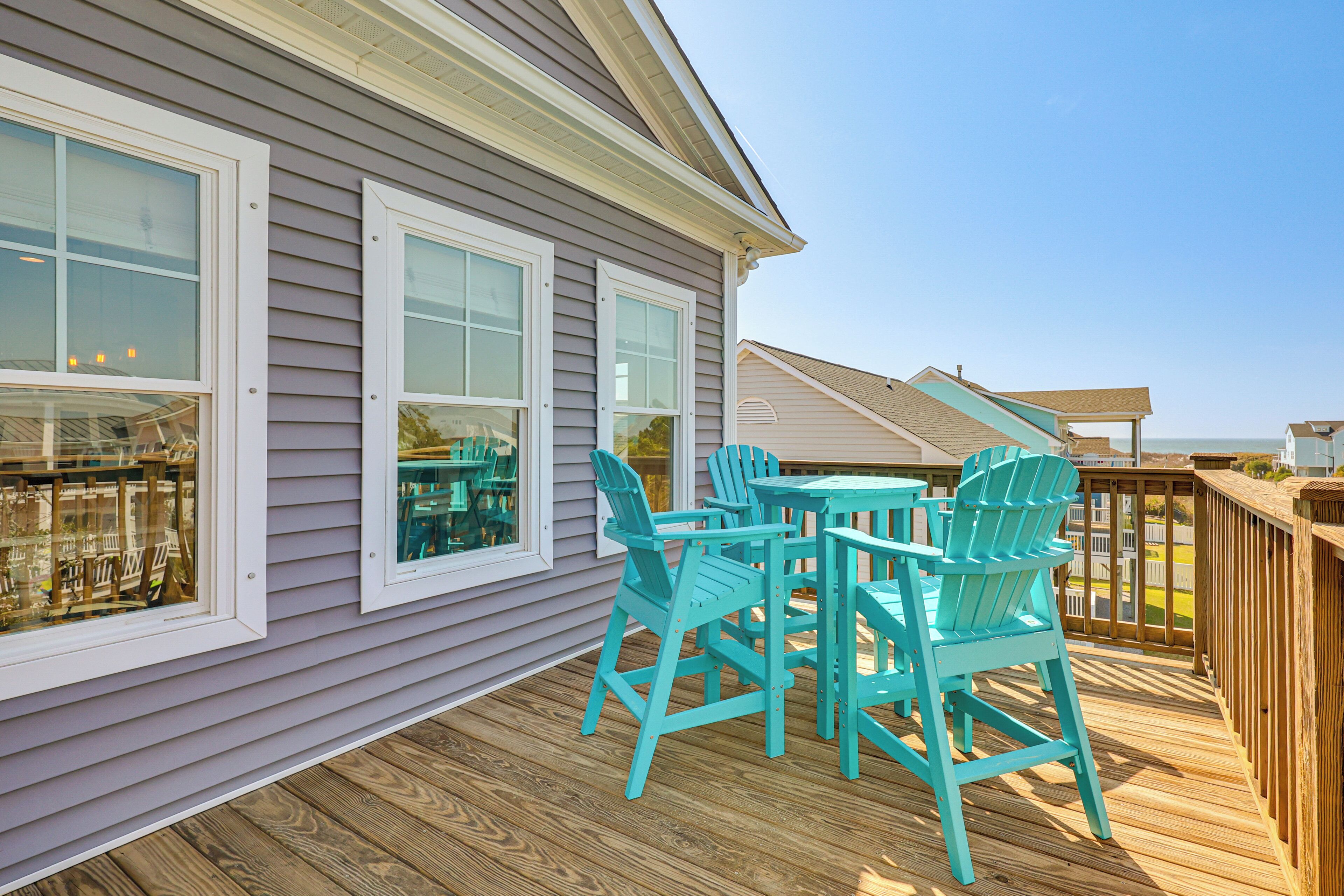 A deck with outdoor furniture and a view of the ocean.