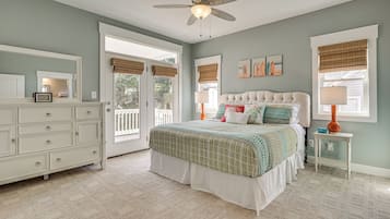 A bedroom with a bed, dresser, ceiling fan, and windows with blinds.