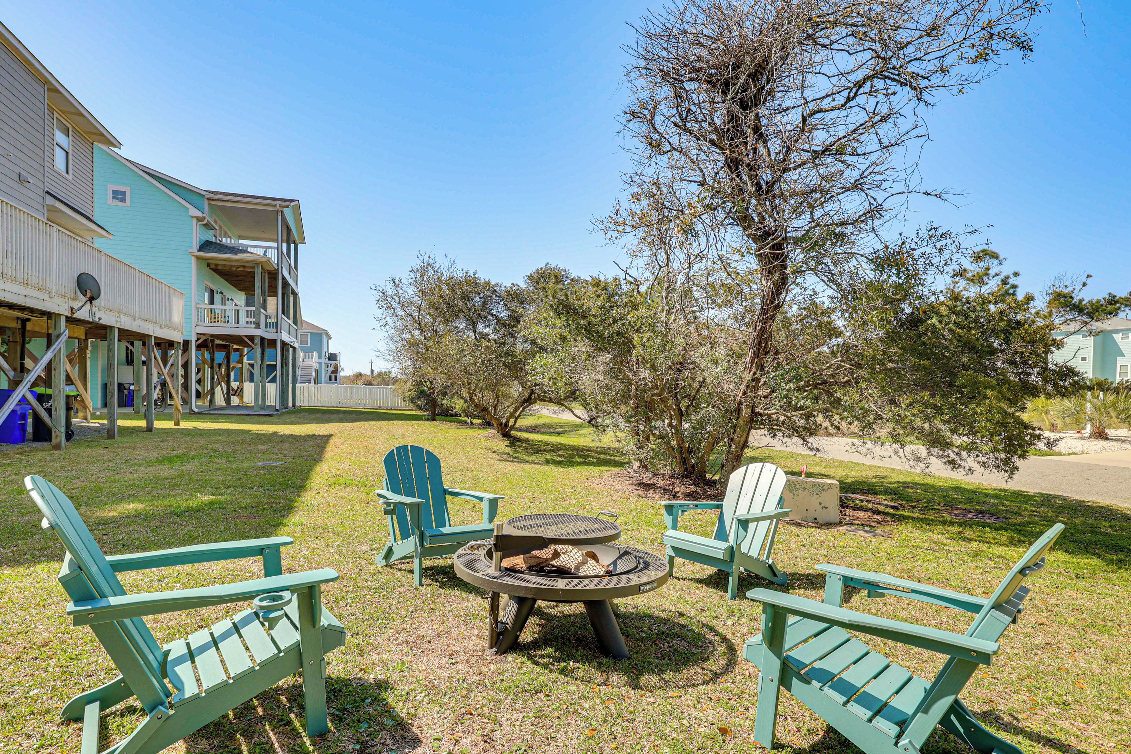 Une terrasse avec des fauteuils Adirondack, un foyer extérieur et un bâtiment doté d’un balcon.