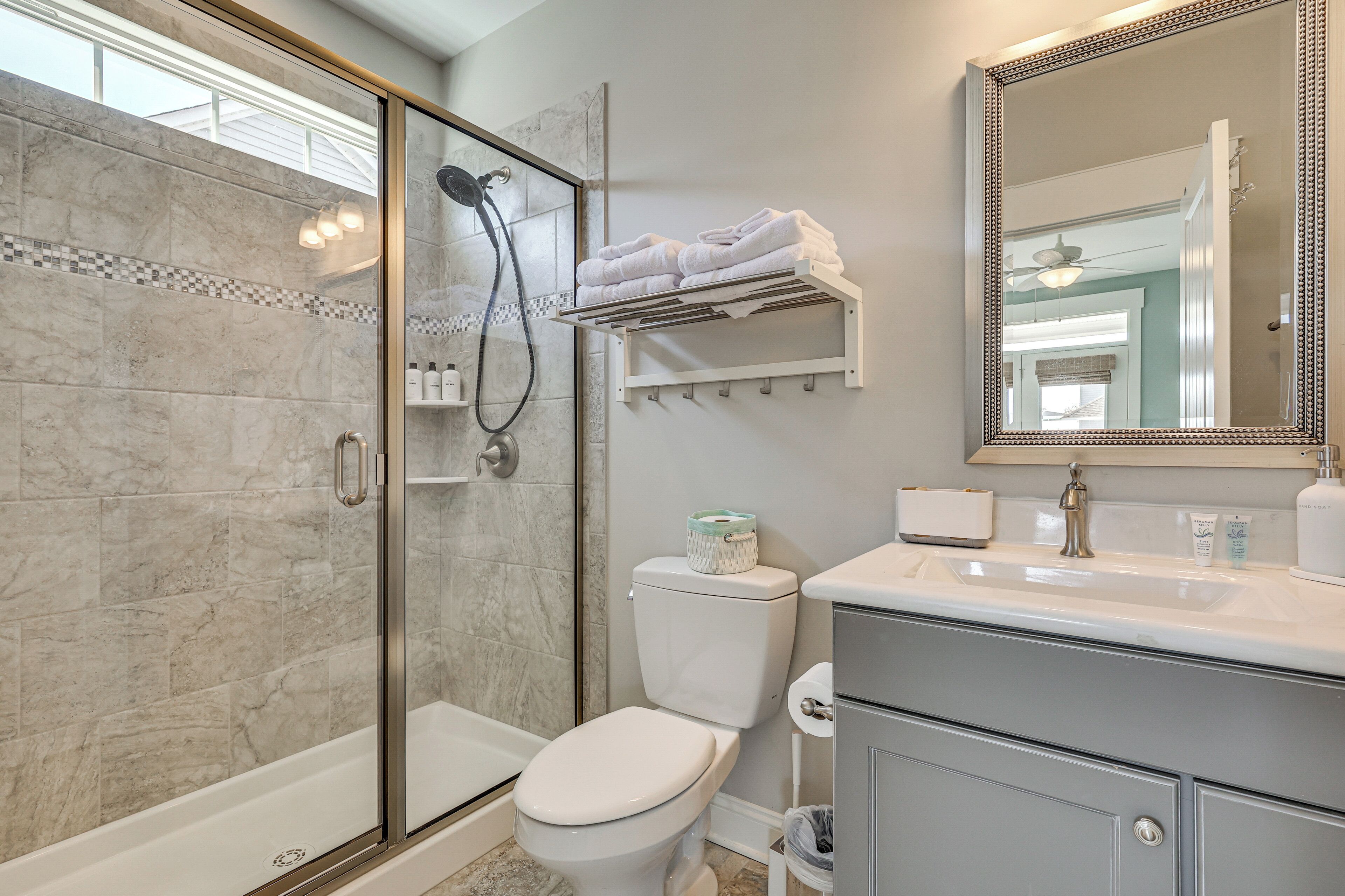 A bathroom with a glass-enclosed shower, a toilet, a sink, and a mirror.