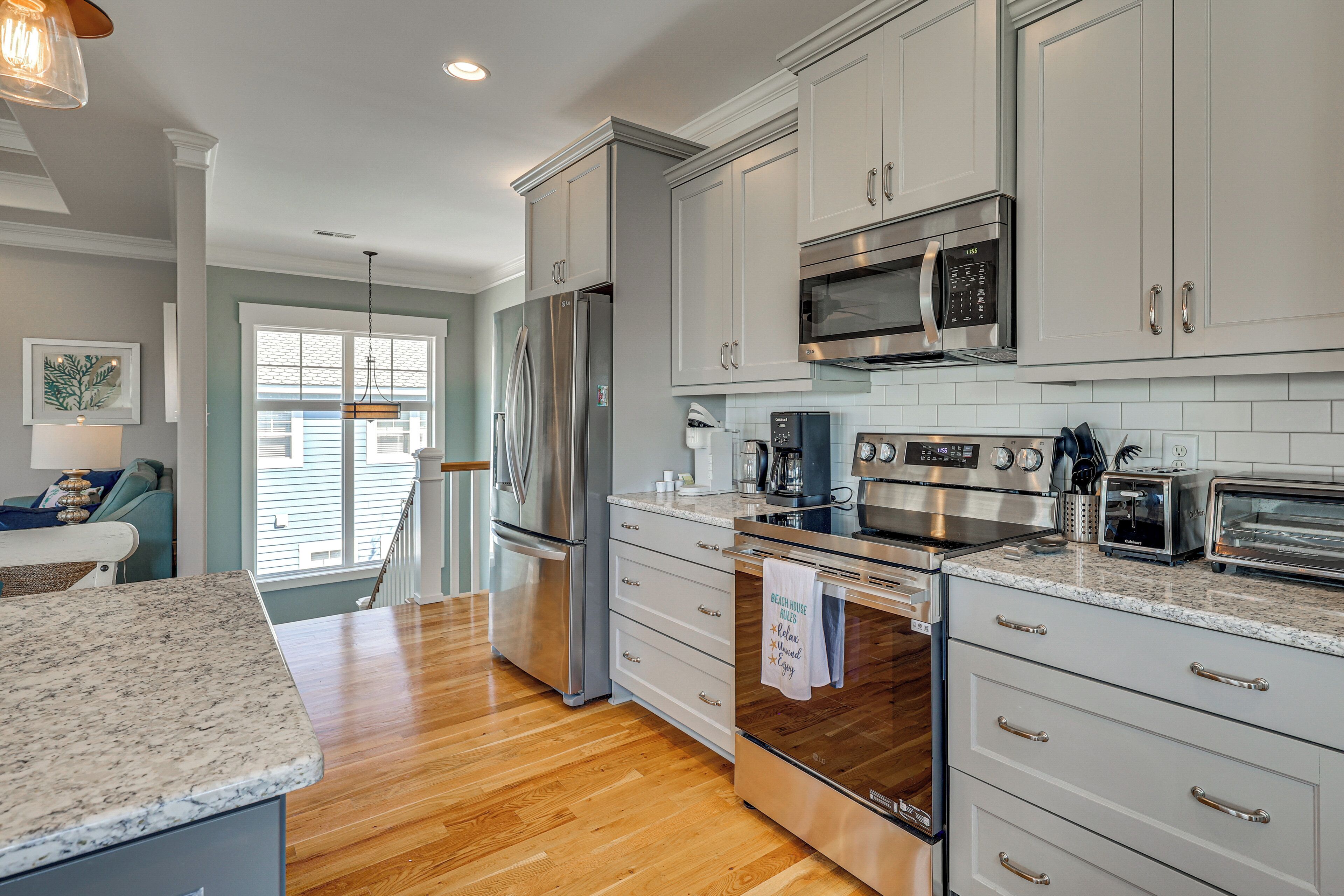 A modern kitchen with stainless steel appliances, white cabinetry, and a granite countertop.