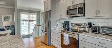 A modern kitchen with stainless steel appliances, white cabinetry, and a granite countertop.
