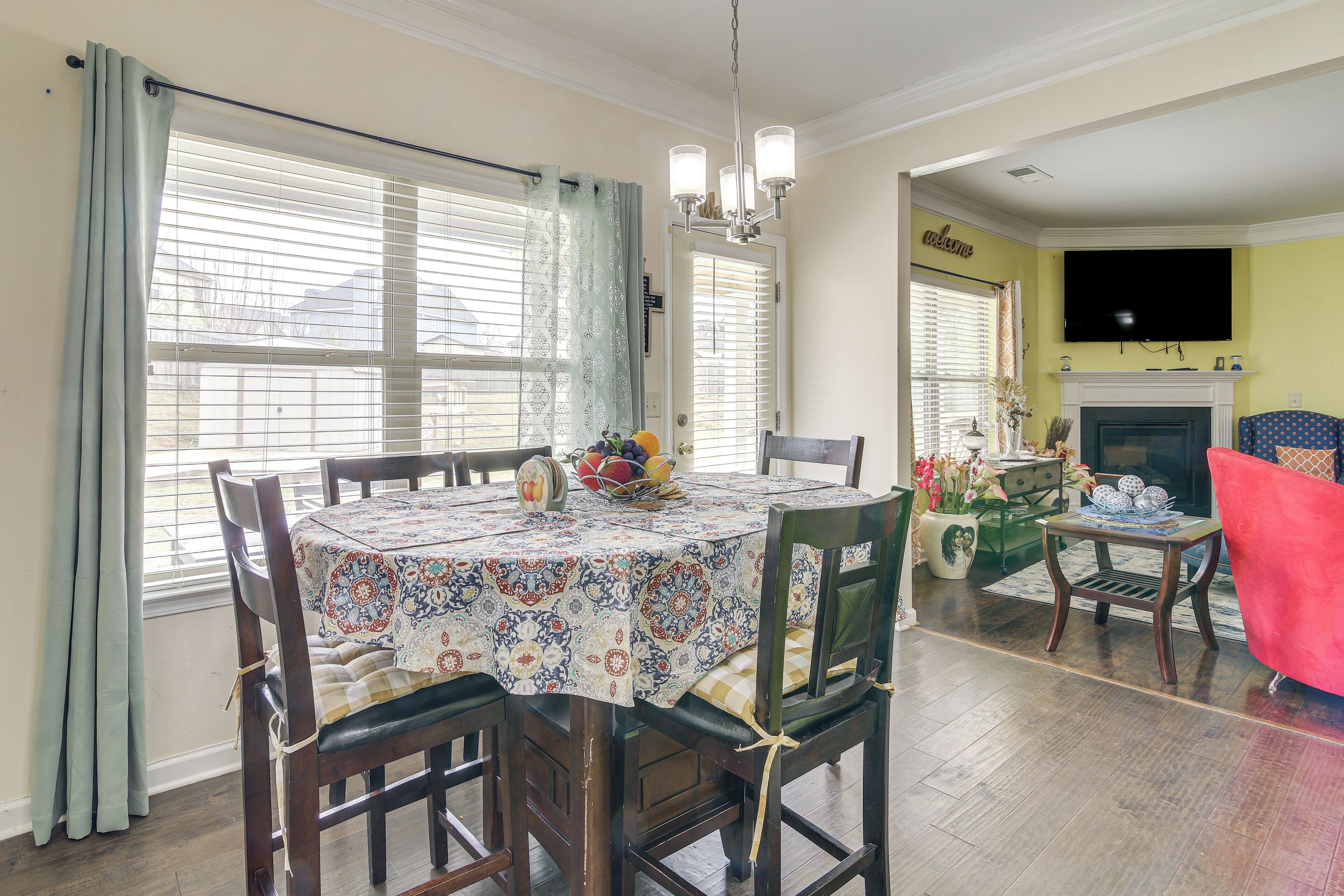 Un coin repas avec une table dressée pour quatre personnes, une cheminée et un téléviseur fixé au mur.