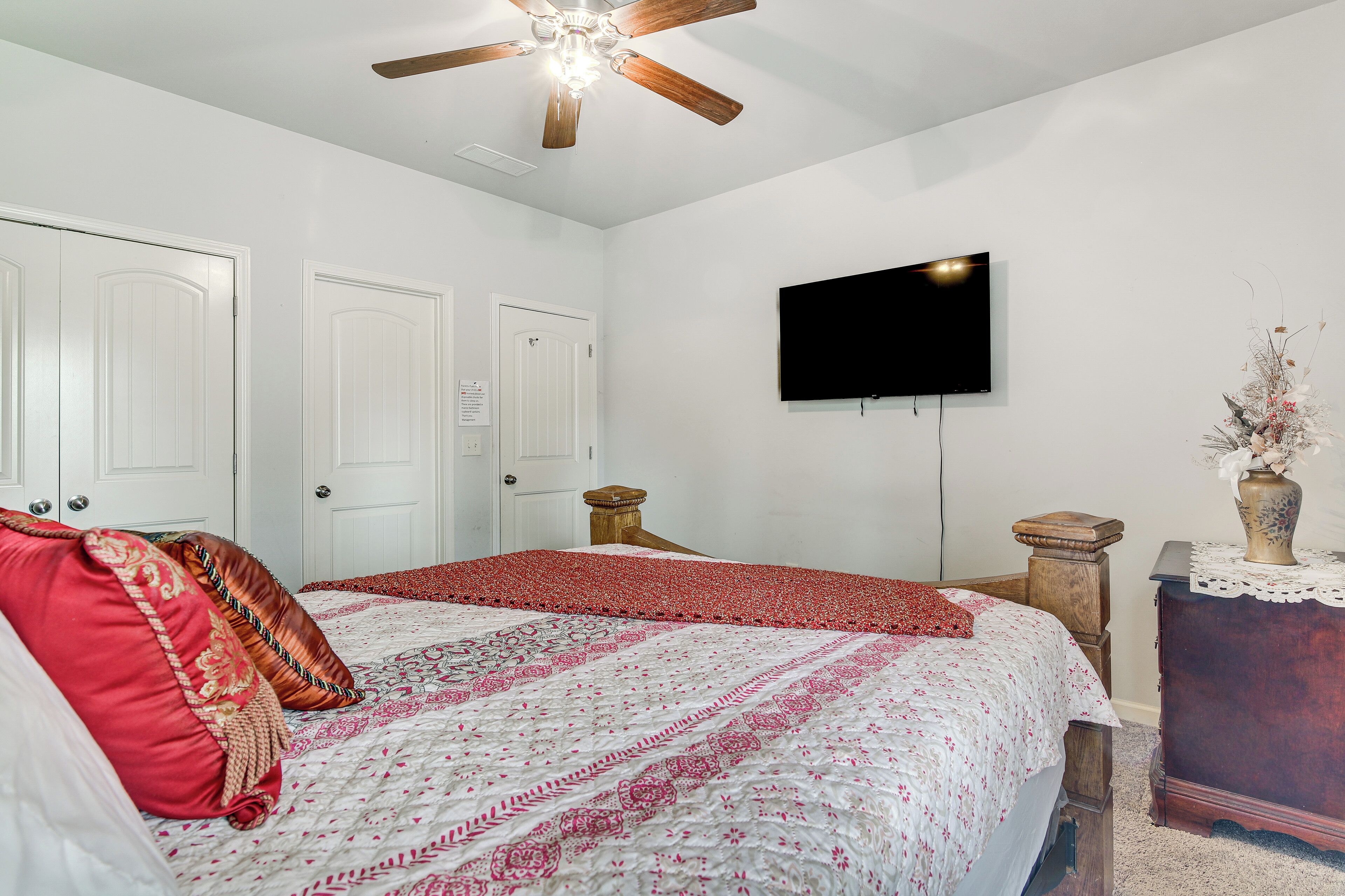 A bedroom with a bed, a ceiling fan, a TV, and a nightstand.