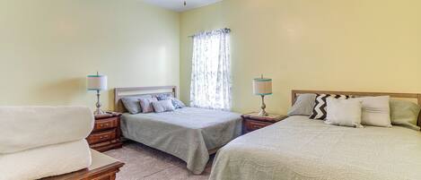 A bedroom with two beds, a ceiling fan, and a window with curtains.