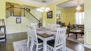 A dining area with a table set for four, a staircase, and a living room with a sofa and a chandelier. - 8 Mi to Dtwn & Film Sites! Spacious Covington Home (Covington)