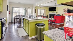 A kitchen with a central island, a dining area with chairs, a TV mounted on the wall, and a fireplace. - 8 Mi to Dtwn & Film Sites! Spacious Covington Home (Covington)