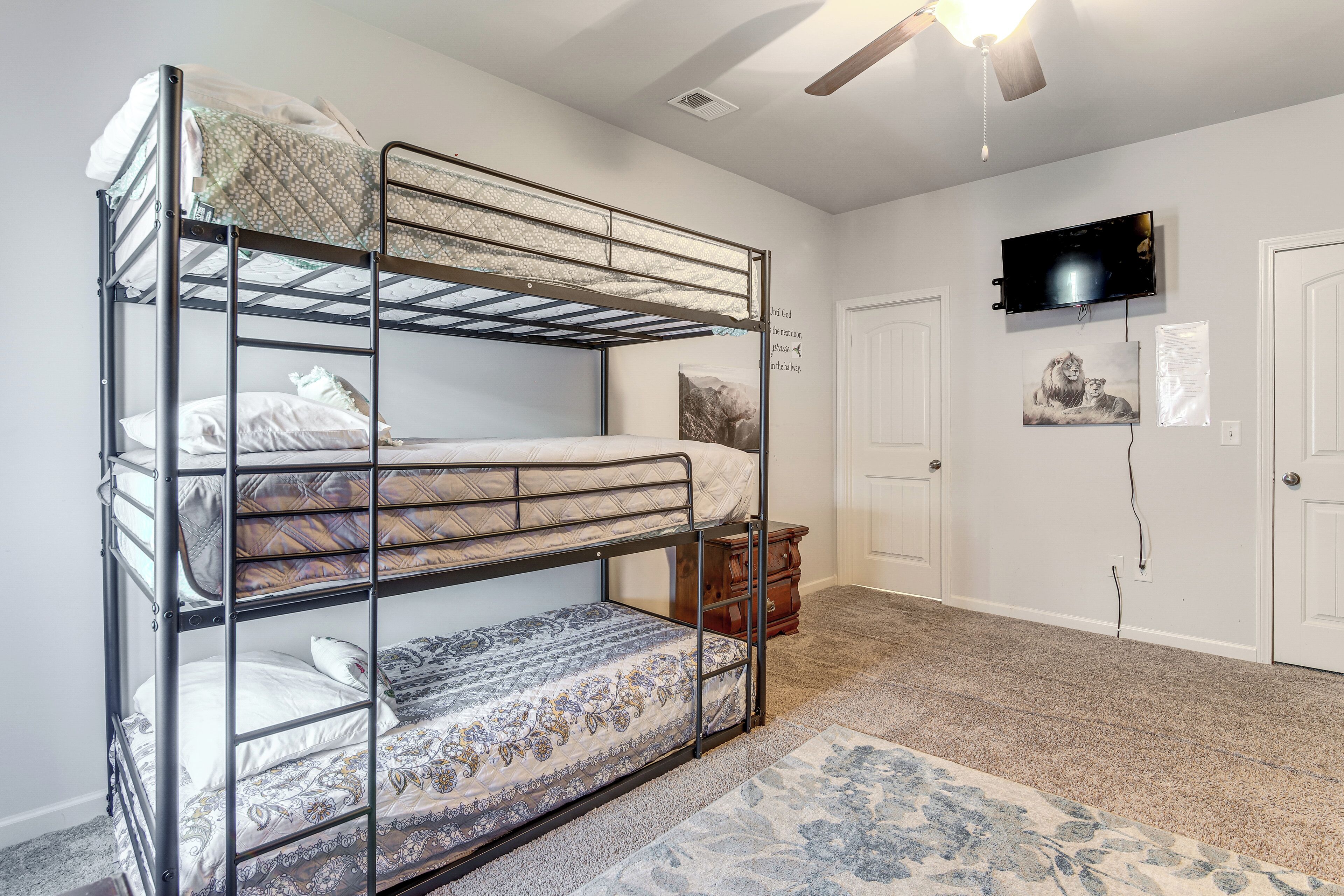 A bunk bed room with a ceiling fan, a television, and a door.