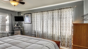A bedroom with a large bed, a ceiling fan, a TV, and a desk with a computer. - Unit 8: Explore the Strip! Studio w/ Pool Access (Lake Ozark)