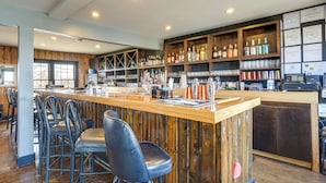 A bar area with wooden shelves, bar stools, and a counter. - Unit 8: Explore the Strip! Studio w/ Pool Access (Lake Ozark)