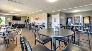 A spacious indoor area with multiple tables and chairs, a reception desk, and a wall-mounted television. - Unit 8: Explore the Strip! Studio w/ Pool Access (Lake Ozark)