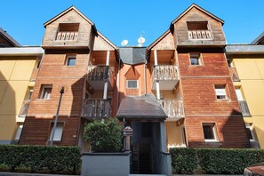 Um edifício de madeira de dois andares com varandas, entrada central e uma placa com a inscrição 'Vacances'.