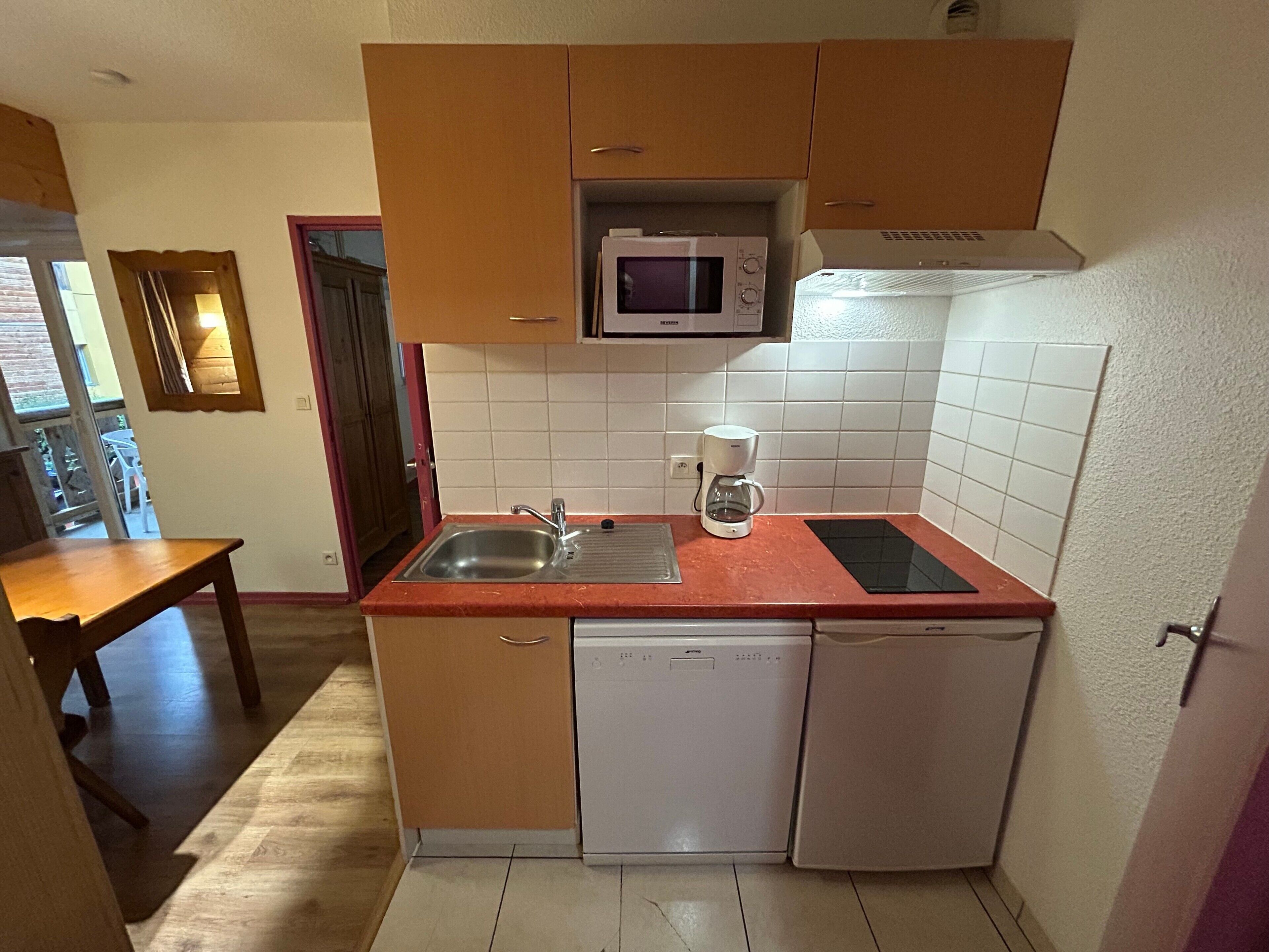 Cocina compacta equipada con microondas, cafetera y lavavajillas.