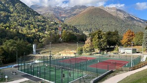 A tennis court with a net, surrounded by a fence, and a mountain backdrop. - L'Izard, Pool & Spa, Parking (Cauterets)