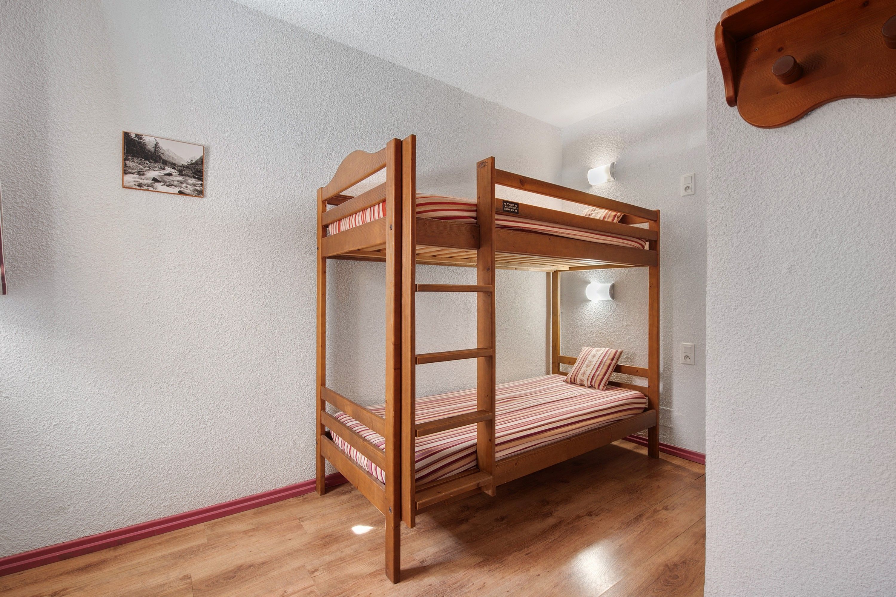 Un lit superposé avec une structure en bois et une literie à rayures.