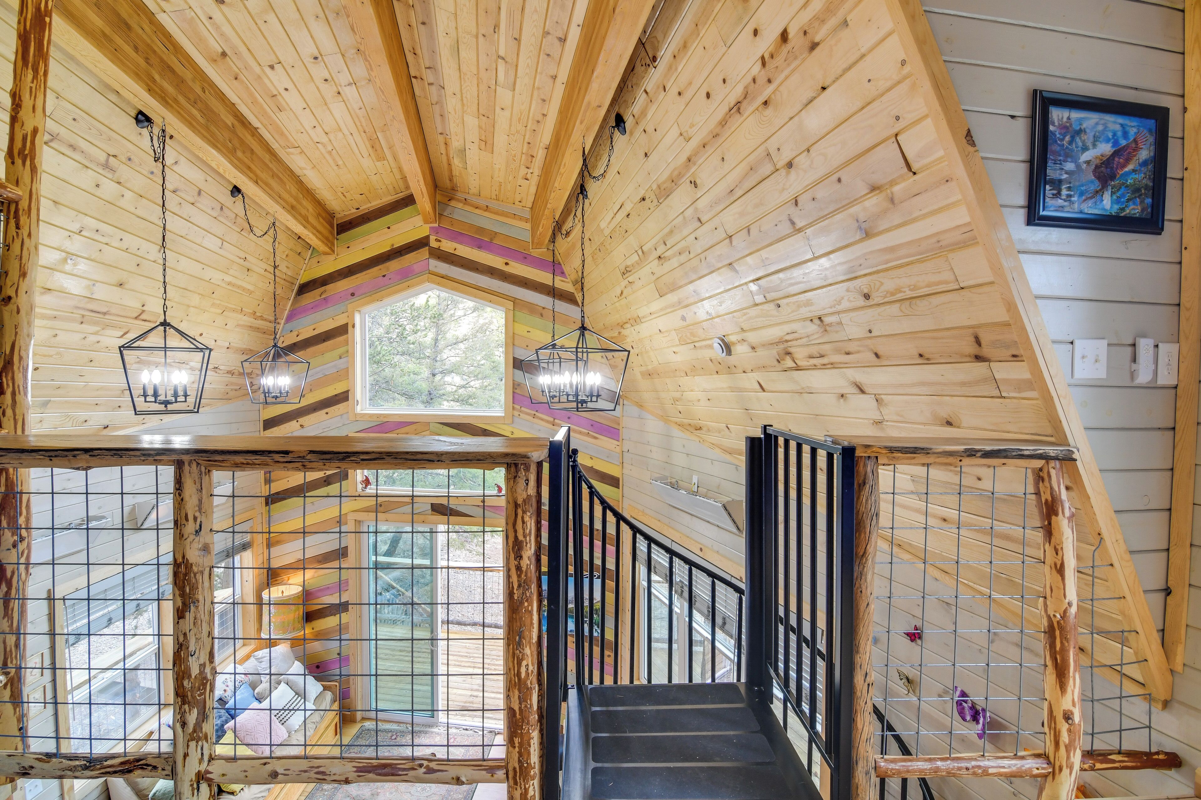 A wooden interior with a staircase, hanging lanterns, and a window.