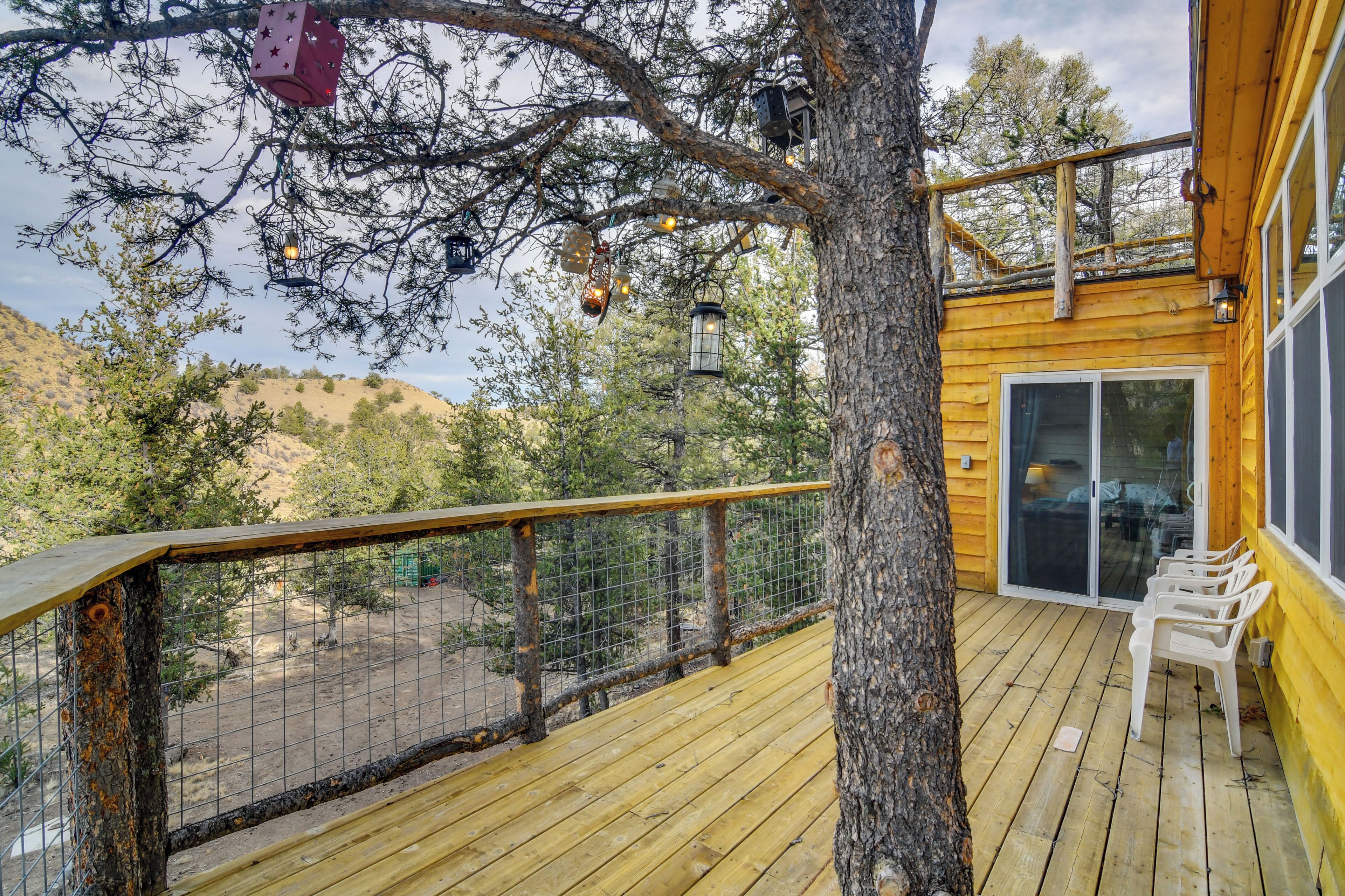 Une terrasse en bois avec une rambarde, un arbre et un bâtiment doté d’une porte en verre.
