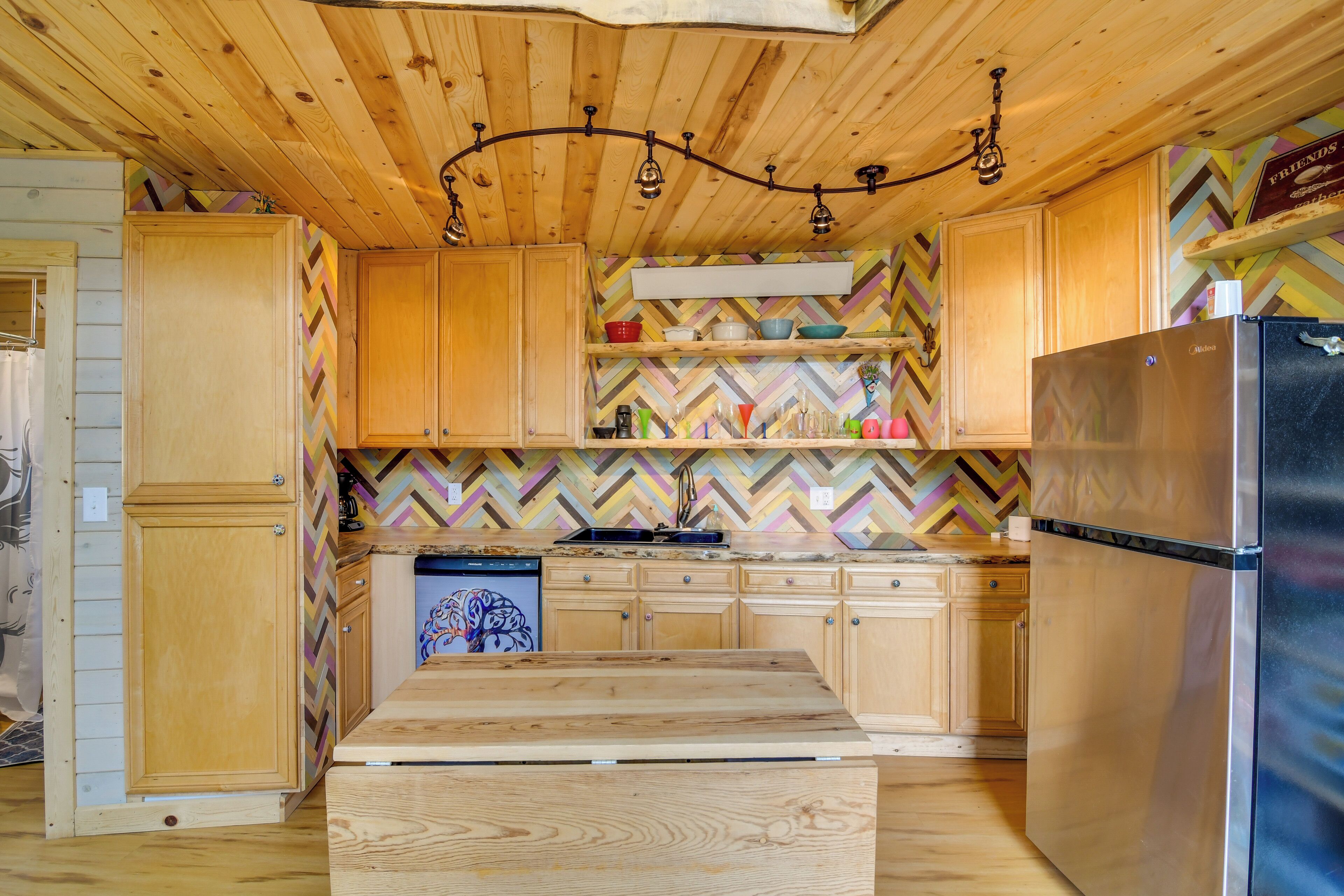 Une cuisine avec des meubles en bois, un réfrigérateur en acier inoxydable et un dosseret décoré d’un motif en chevrons.
