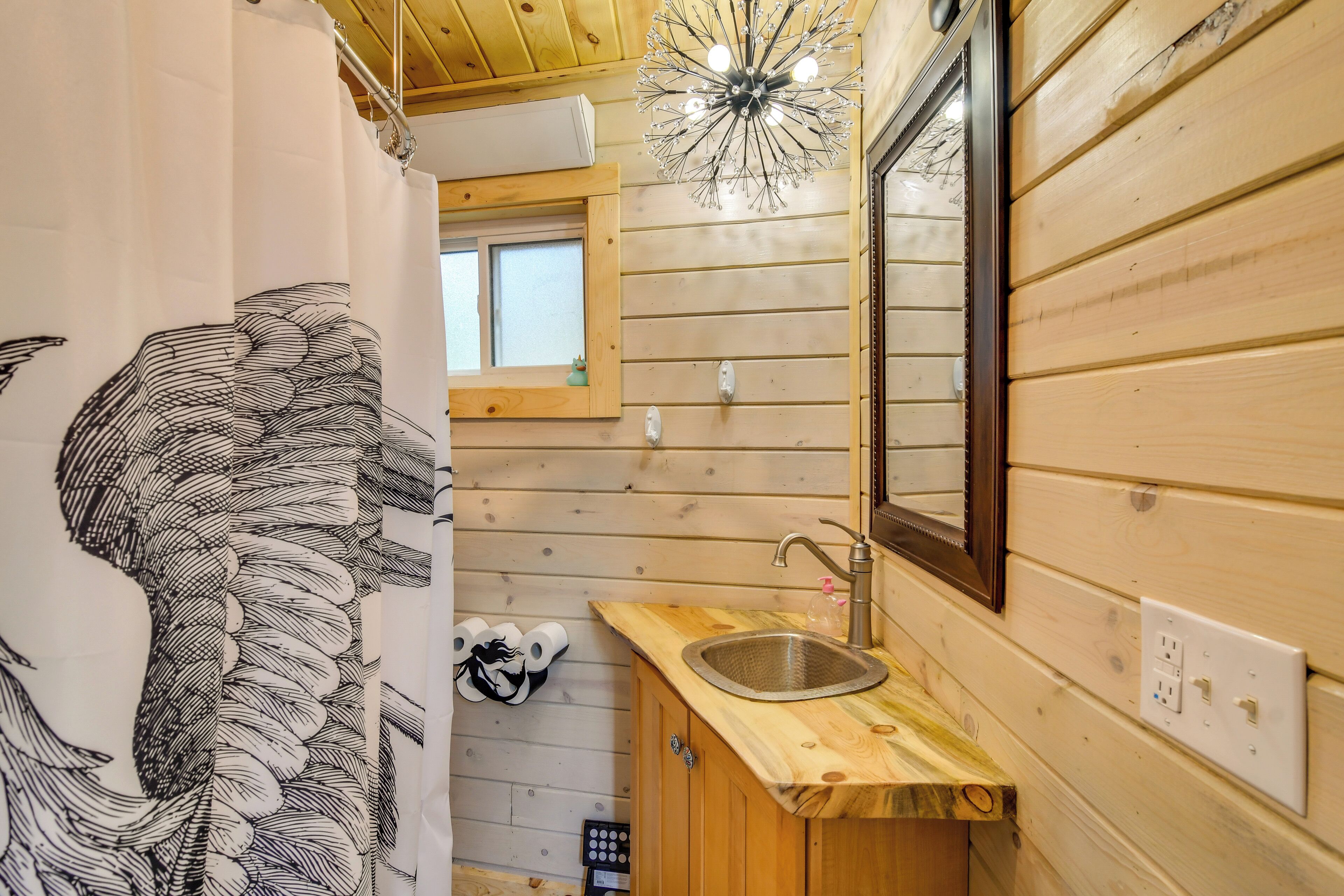 A wooden interior with a sink, mirror, and window.