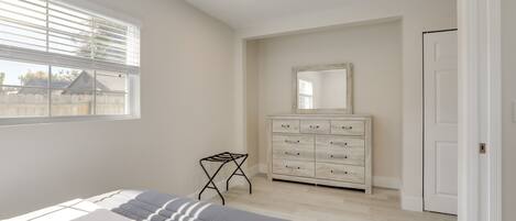 Un dormitorio con cama, cómoda, espejo y ventana con persianas.